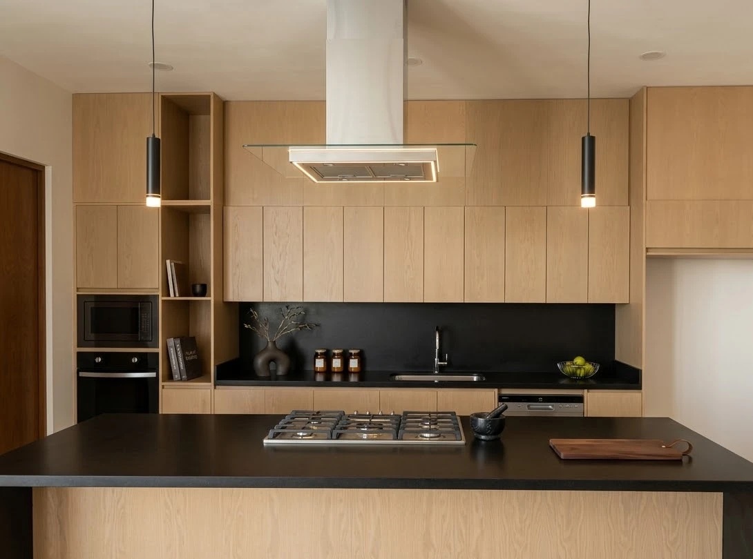 Cocina con gabinetes de roble, campana con luz LED e isla con cubierta negra